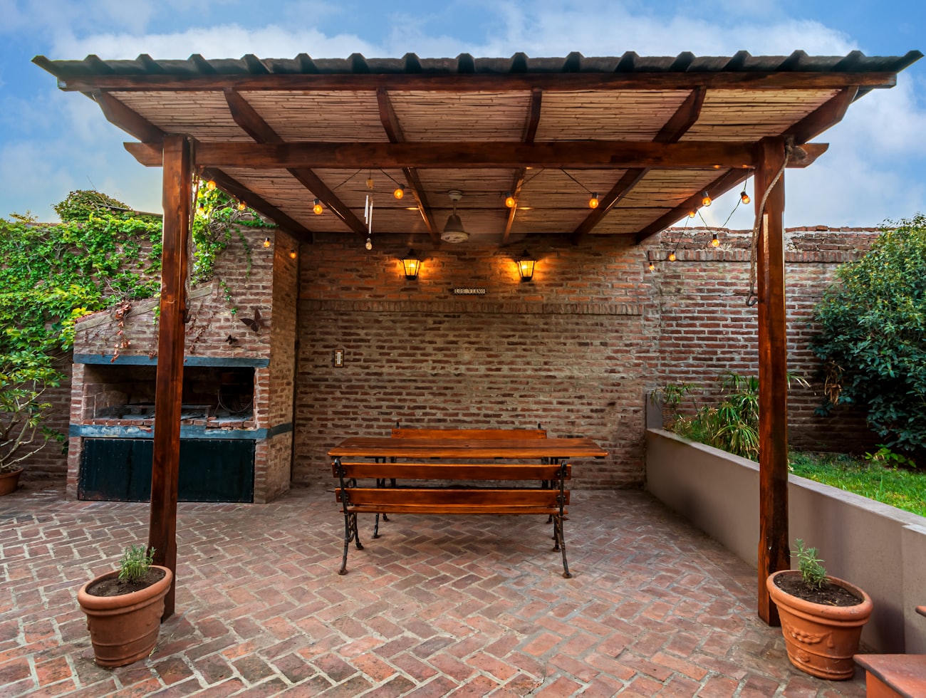 Covered pergola over a brick patio with warm string lighting